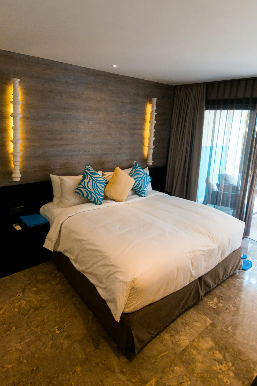 The bed at night with the wall lamps glowing and blue cushions